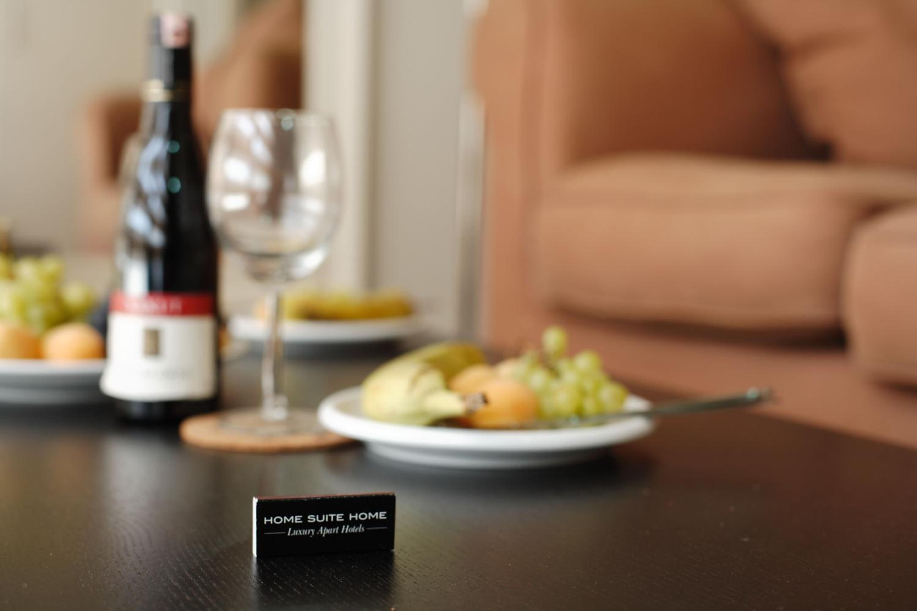 Ein Tisch mit einer Weinflasche, einem Weinglas und einer Obstplatte.