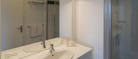A bathroom with a white sink, mirror, and shower.
