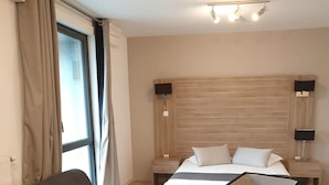 Ett modernt hotellrum med en stor säng, en soffa, ett litet bord och två sängbord med lampor.