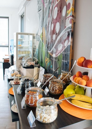 A buffet setup with various food items and a fruit display. - Twenty Business Flats Lille Grand Stade (Villeneuve-d'Ascq)