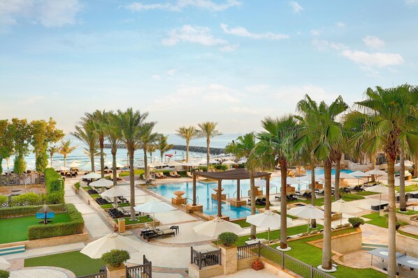 A resort pool area with lounge chairs, umbrellas, and palm trees. - Ajman Saray, a Luxury Collection Resort, Ajman (Ajman)