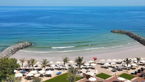 A beach resort with sun loungers, umbrellas, and a rocky breakwater. - Ajman Saray, a Luxury Collection Resort, Ajman (Ajman)