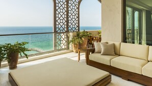 A balcony with a sofa, chairs, and potted plants, overlooking a clear blue sea. - Ajman Saray, a Luxury Collection Resort, Ajman (Ajman)