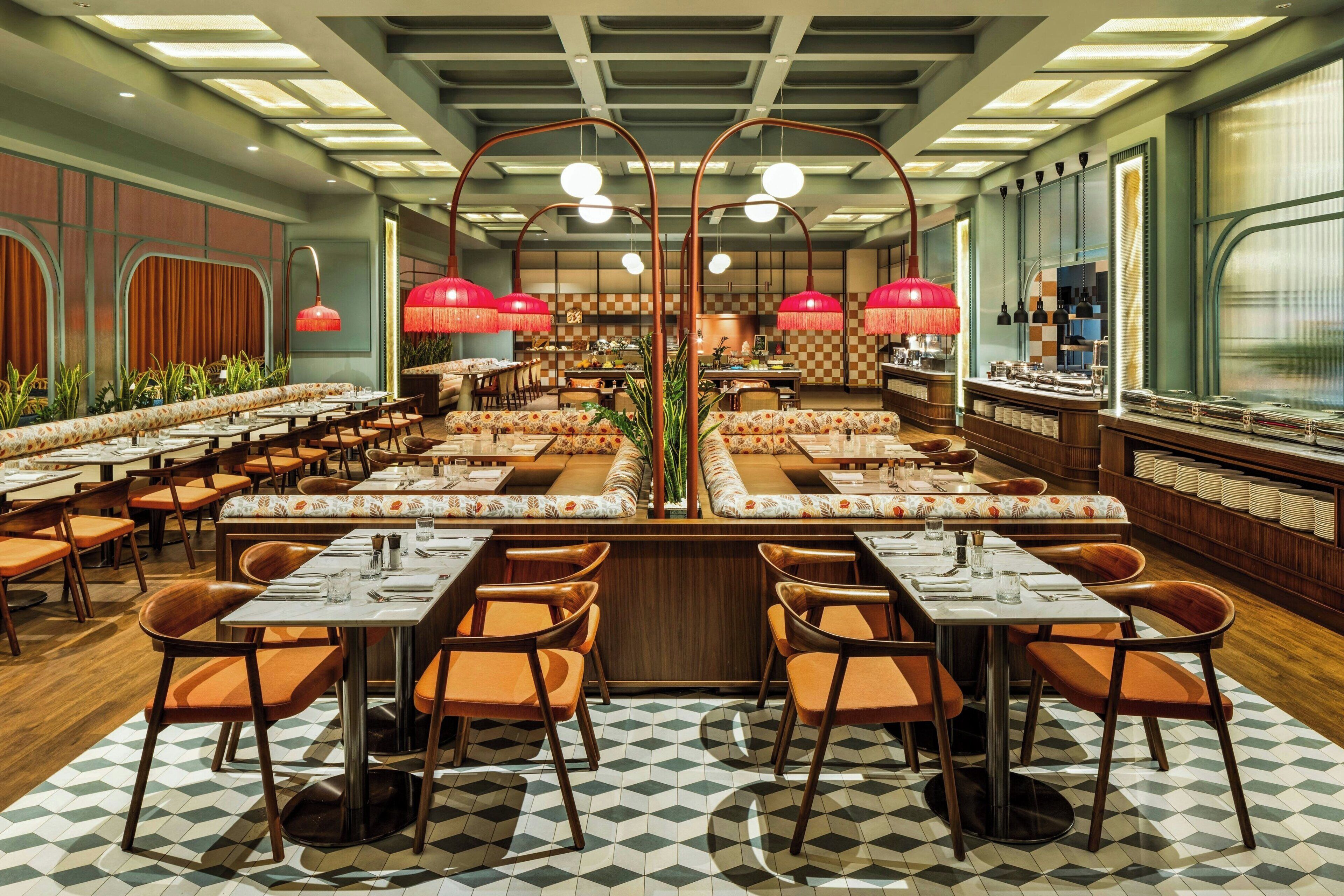 A spacious restaurant with multiple dining areas, each featuring wooden tables and orange chairs.