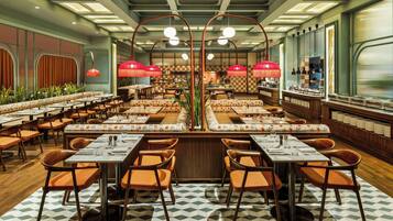A spacious restaurant with multiple dining areas, each featuring wooden tables and orange chairs.
