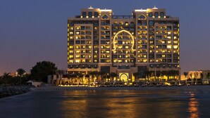 A multi-story hotel with a prominent circular light feature on the facade, located near a beach. - Ajman Saray, a Luxury Collection Resort, Ajman (Ajman)