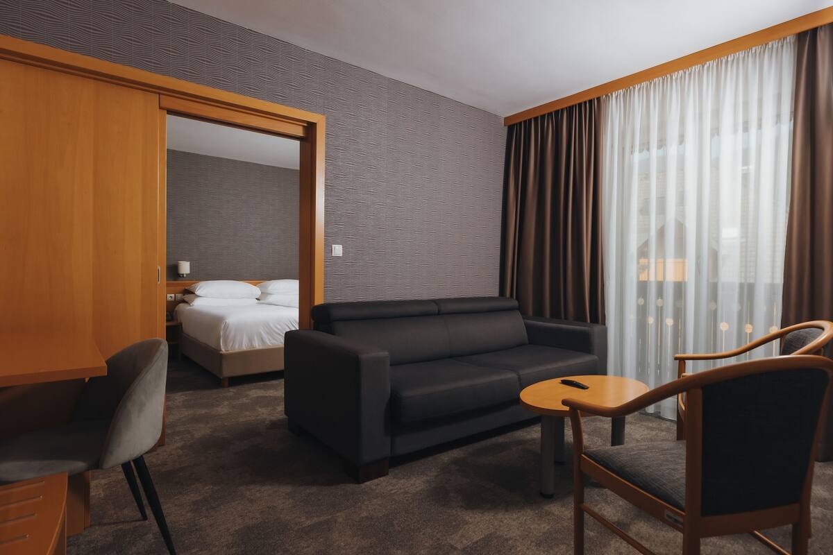 Een hotelkamer met een bed, een zwarte bank, een houten bureau en een stoel.