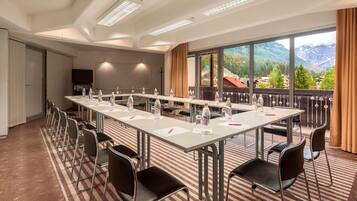 A conference room with a long table, chairs, and a large window with a mountain view.