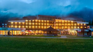 A modern hotel with multiple floors, outdoor seating, and a view of mountains in the background. - Ramada Resort by Wyndham Kranjska Gora (Kranjska Gora)