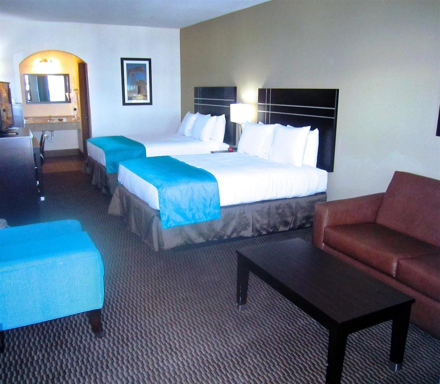 Une chambre d’hôtel avec deux lits, un bureau, une chaise et un canapé.