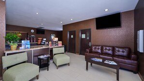 A lobby with a reception desk, seating area, and a television mounted on the wall. - Americas Best Value Inn & Suites Cuero (Cuero)