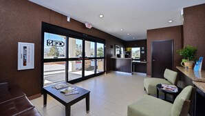 A hotel lobby with a reception desk, seating area, and large windows. - Americas Best Value Inn & Suites Cuero (Cuero)
