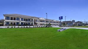 A hotel with a modern design, featuring a long building with multiple floors and a covered walkway. - Americas Best Value Inn & Suites Cuero (Cuero)