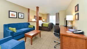 Een hotelkamer met een blauwe bank, een houten bureau, een bed en een stoel.