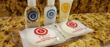 Three bottles of RAIO hair care products and two packets of RAIO Shea Butter Soap on a granite countertop.