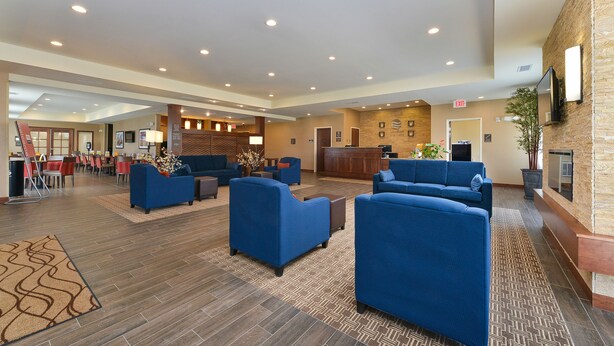 Een ruime lobby met blauwe banken, een receptiebalie en een open haard.