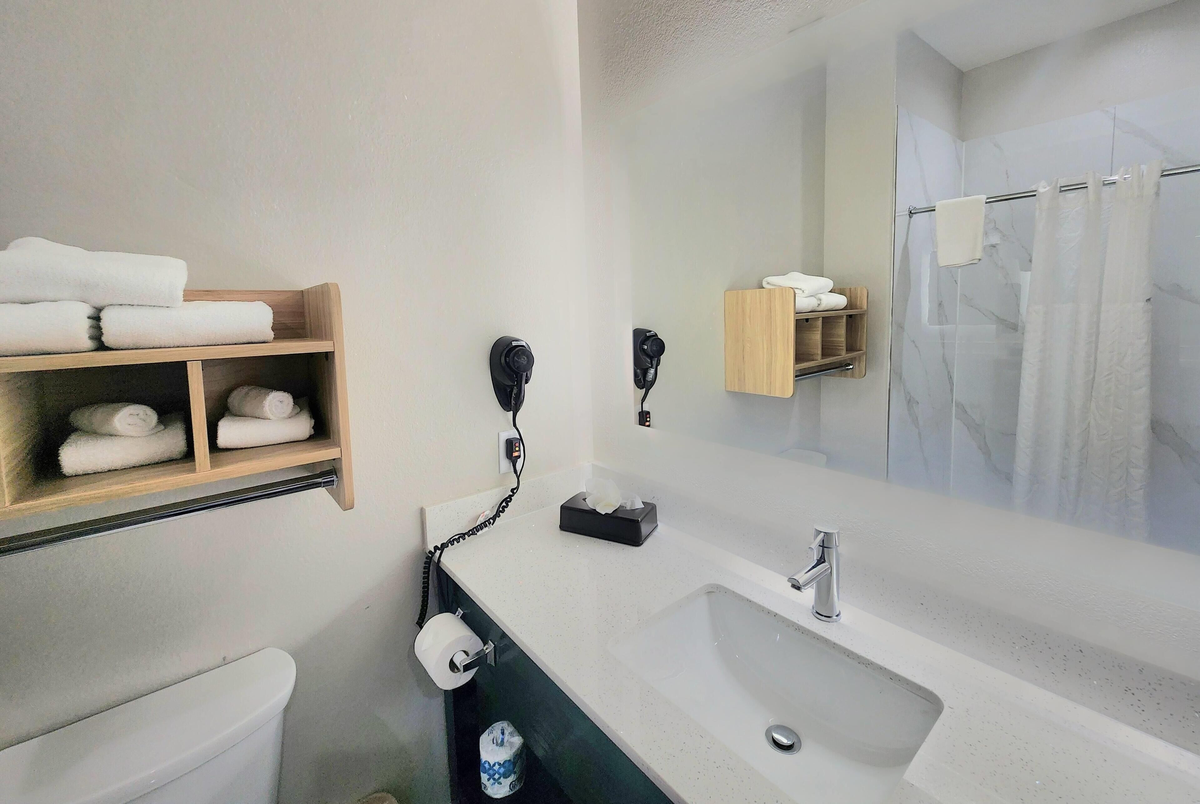 A bathroom with a white sink, a mirror, a towel rack, and a toilet.