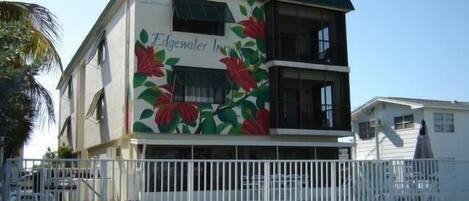 A two-story building with a green roof and a mural of red flowers on the side.