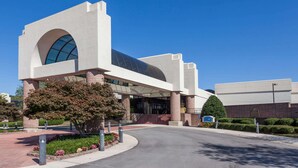 A modern building with a large arched entrance, a glass facade, and a well-maintained garden area.