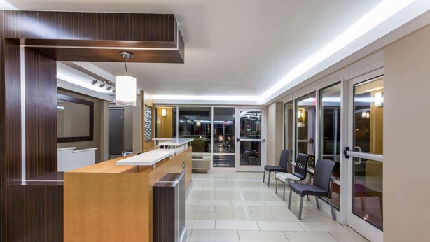 A modern reception area with a wooden reception desk, a flat-screen TV, and a seating area with chairs and a table.