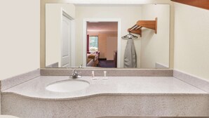 A bathroom with a granite countertop sink, a mirror, and a towel rack.