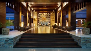 A modern hotel lobby with a central staircase, seating area, and a reception desk. - Savoy Seychelles Resort & Spa (Mahé Island)