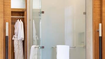 Un baño moderno con ducha de vidrio, vestidor y una bañera grande.