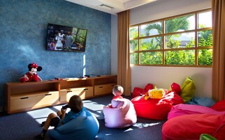 Un niño jugando con una cámara en una habitación con un ventanal grande, un televisor y un peluche de Minnie Mouse.