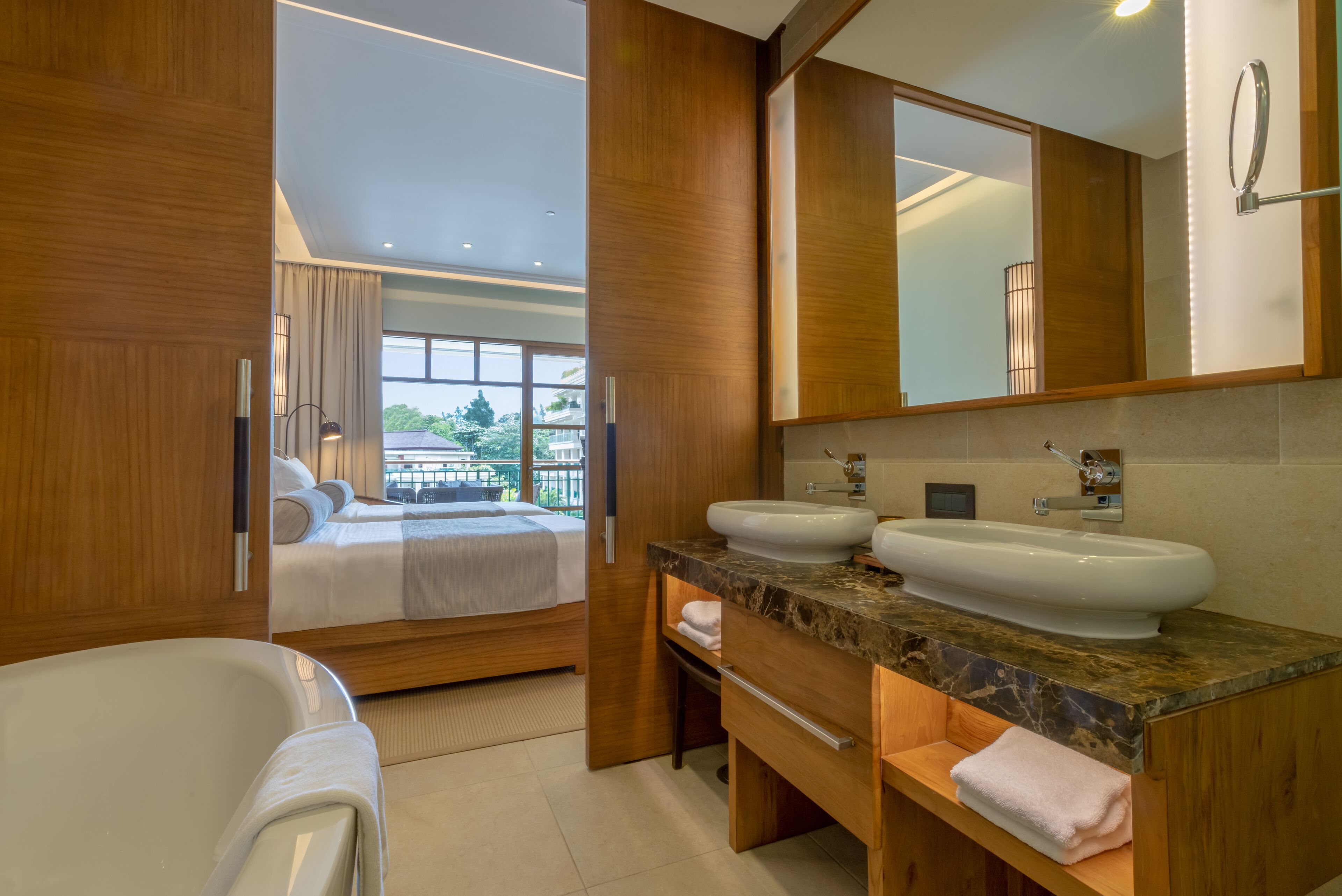 A modern bathroom with a double sink, a large mirror, and a bathtub.