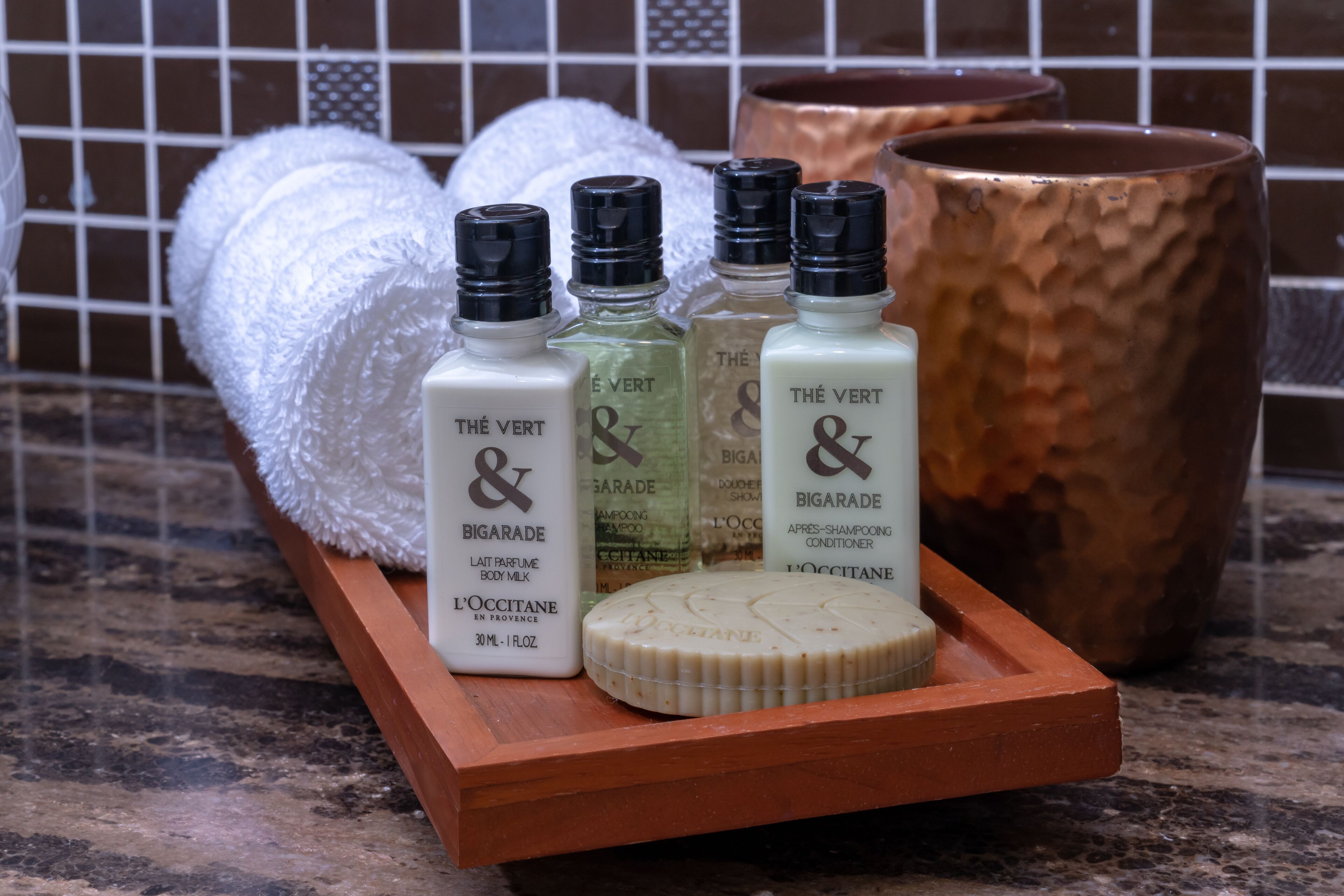 A tray with four bottles of The Vert & Bigarade body milk and a bar of soap.