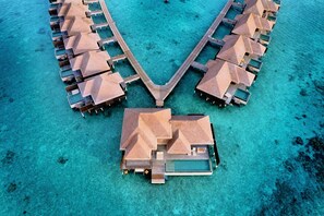 An overwater resort with multiple bungalow-style accommodations connected by a central walkway.