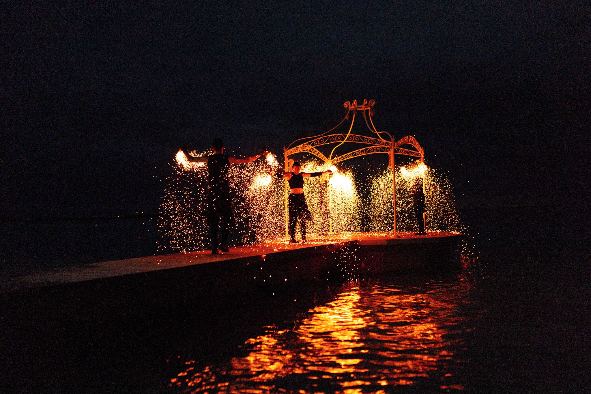 Escena nocturna con una fuente y una estructura parecida a un puente.