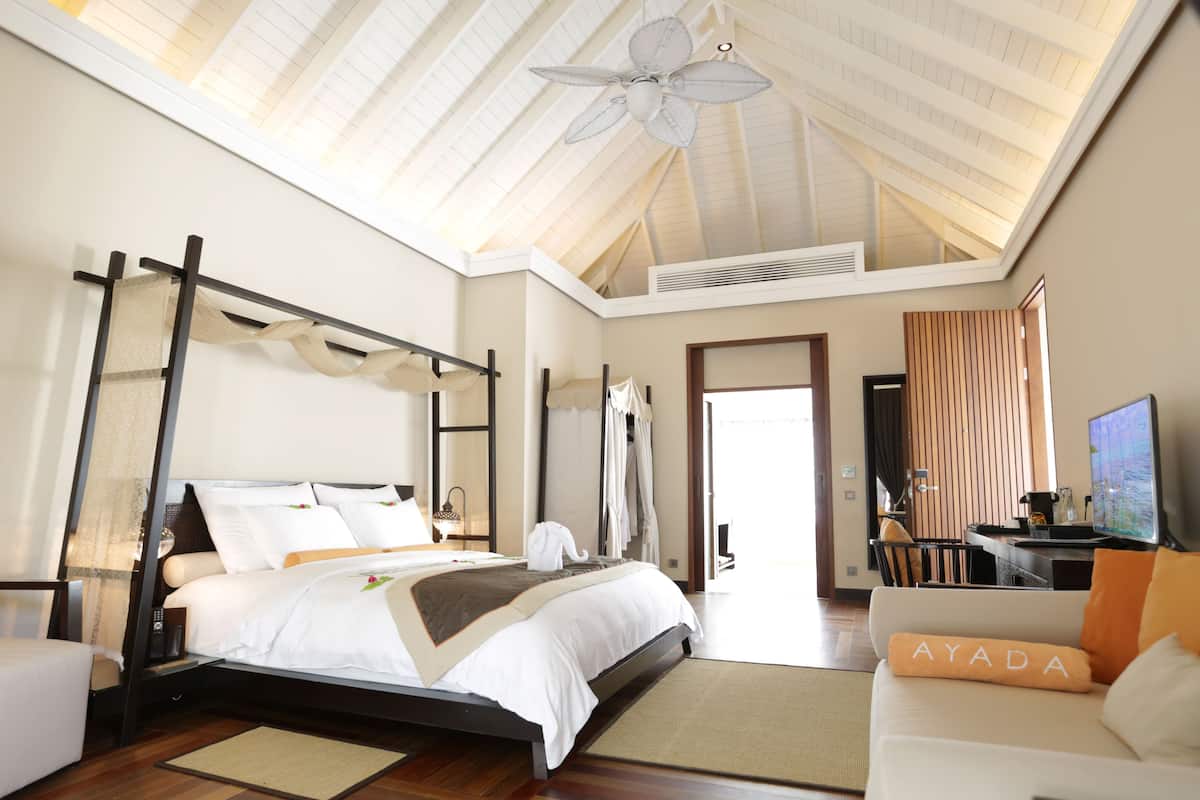 A spacious bedroom with a large bed, a ceiling fan, and a view of the outdoors.