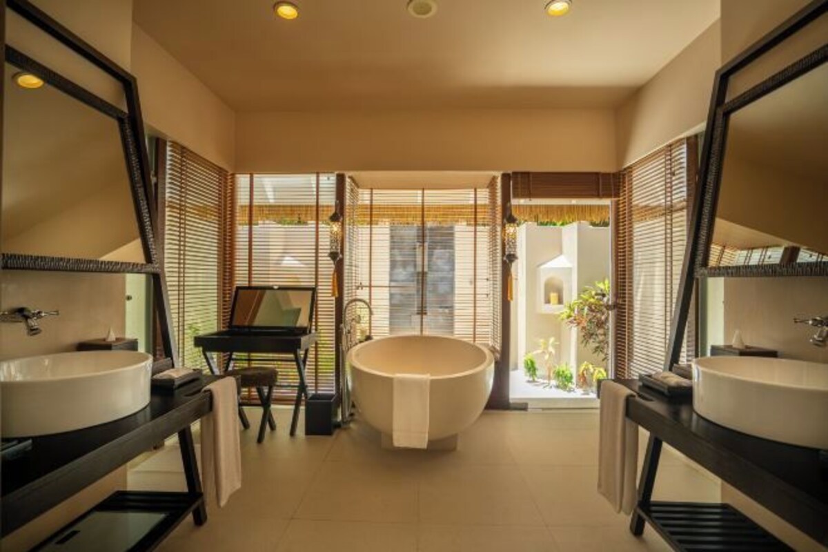 A modern bathroom with two sinks, a bathtub, and a view of the outside.