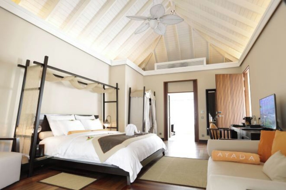 A spacious bedroom with a large bed, a ceiling fan, and a view of the outdoors.