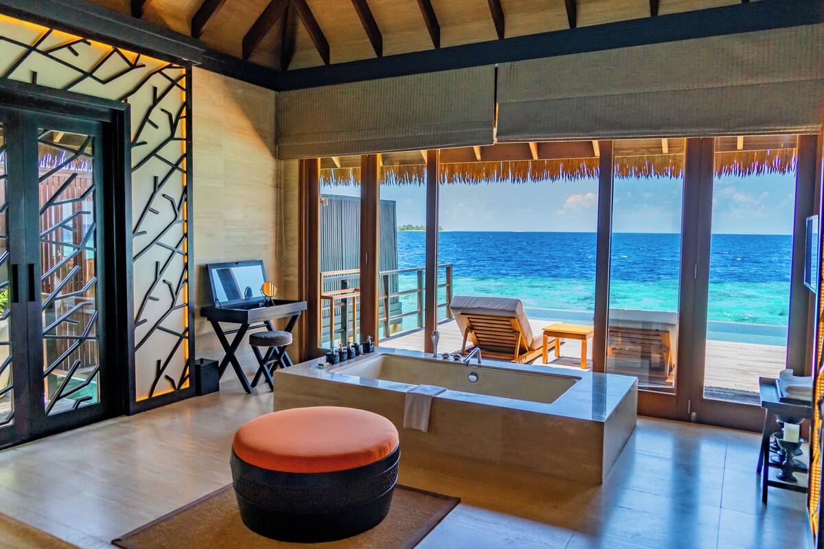 A room with a large bathtub, a desk, and a view of the ocean.