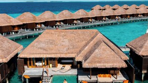 Overwater bungalows with thatched roofs, clear turquoise water, and a wooden walkway connecting them. - Ayada Maldives (Maguhdhuvaa)