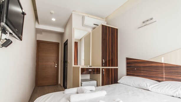 Una habitación de hotel con cama, televisor en la pared, armario y espejo.