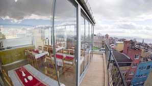 Un comedor con mesas y sillas, ventanas amplias y vista a la ciudad.