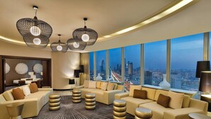 A modern hotel lobby with a curved ceiling, large windows offering a city view, and contemporary furniture.
