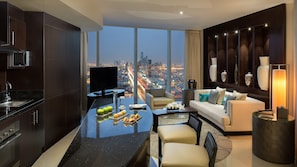 A modern living room with a city view, a kitchen with a microwave, and a dining area with a glass table.