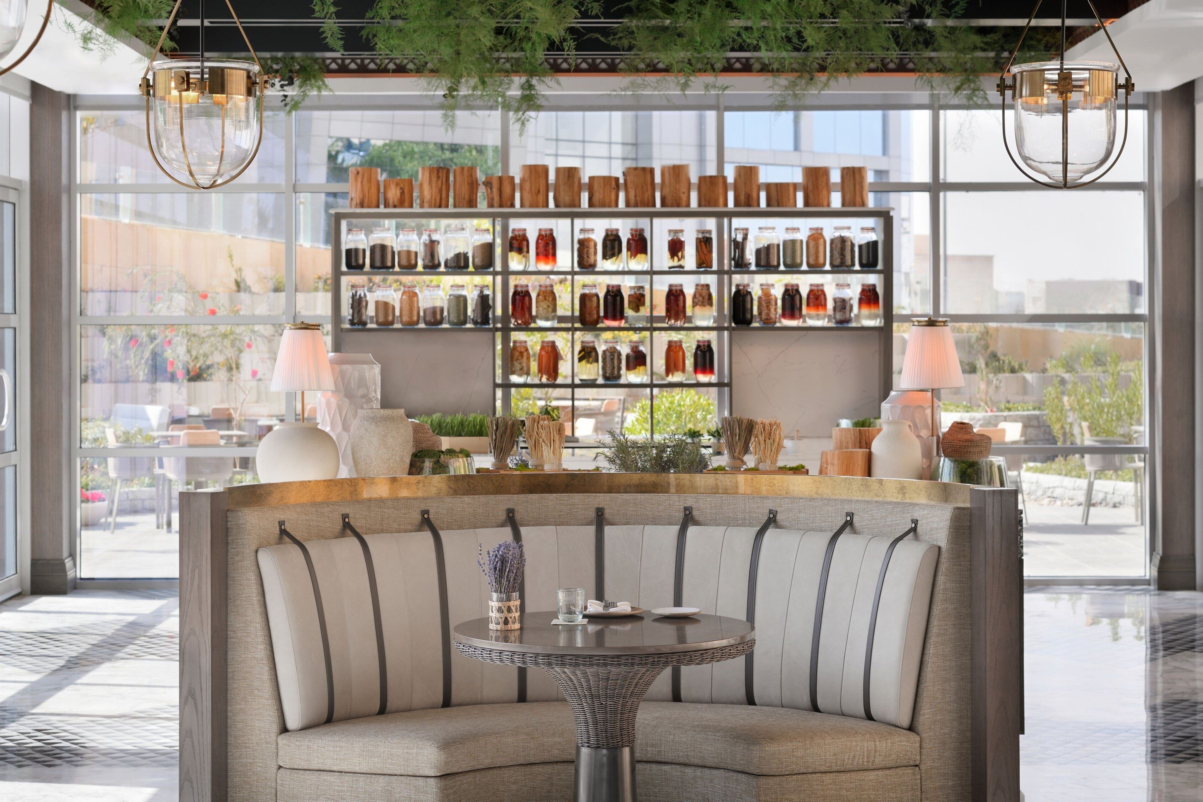 A modern interior with a curved sofa, a round table, and a wall of glass jars.