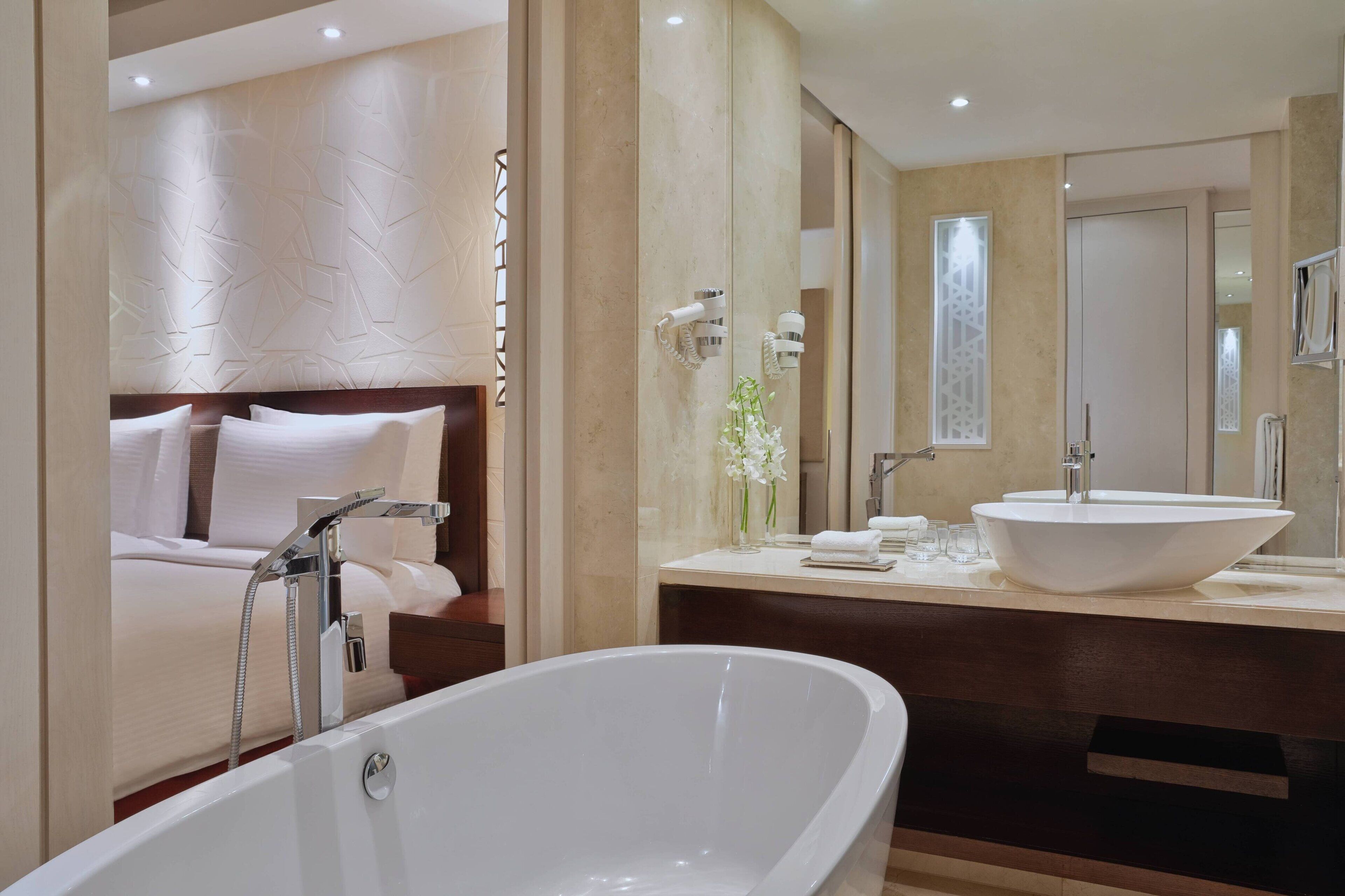 A modern bathroom with a freestanding bathtub, a large mirror, and a double sink vanity.