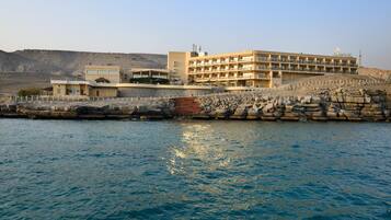 Un hotel frente al mar con varios pisos, una costa rocosa y vistas despejadas al océano.