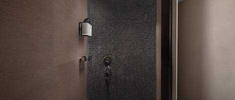 A modern shower area with a curved wall, a handheld showerhead, and a wall-mounted faucet.