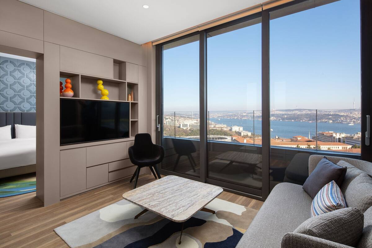 A modern living room with a large window, a flat-screen TV, a sofa, and a coffee table.