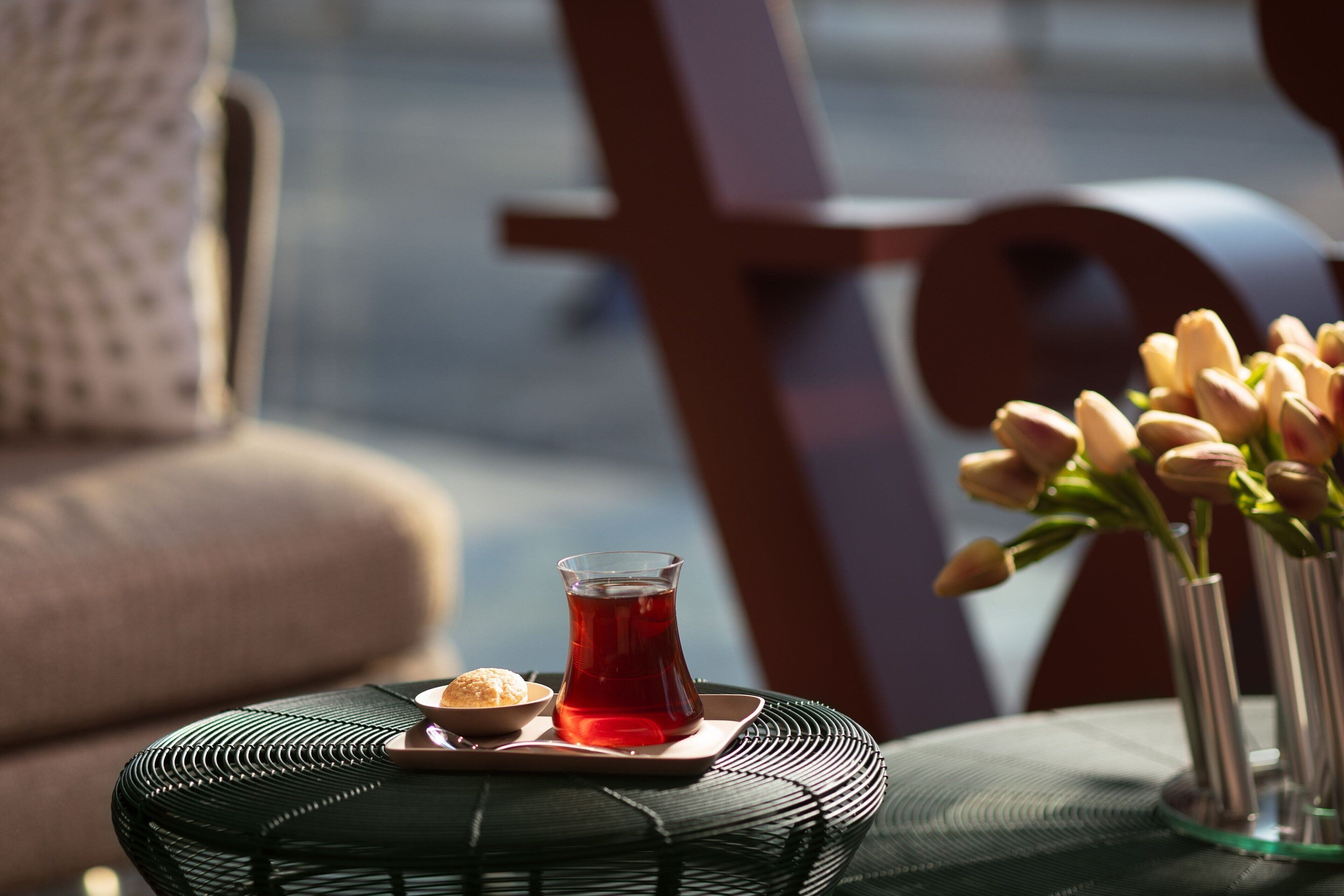 A wicker chair with a tray holding a glass of tea and a small bowl of sweets.