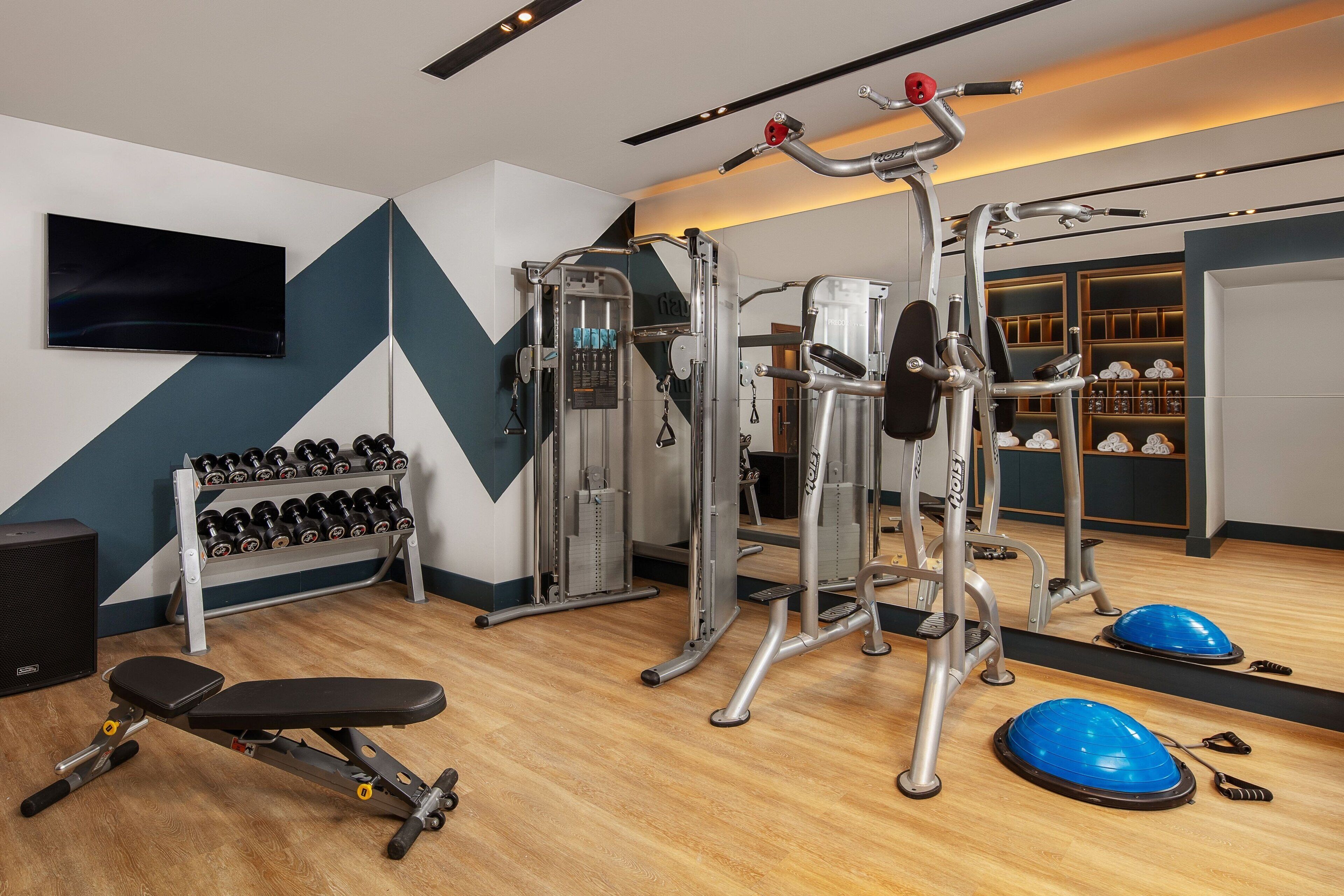 A gym with weight machines, dumbbells, and exercise balls.