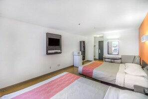 A hotel room with two beds, a television, a refrigerator, and a small desk with a chair. - Motel 6 Regina, SK (Regina)