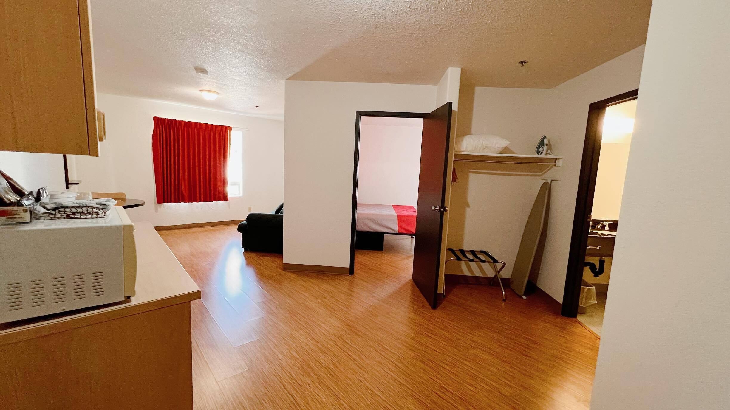 Una habitación compacta con kitchenette, una cama y una pequeña zona de estar.